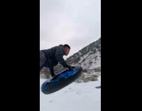 Man on the snow tube sled jumps on the ramp in slow motion