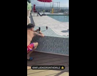 Man shirtless crouches and takes picture of his drink