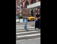 Man holding free sweat sign crossing street 