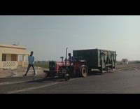 Red tractor tows green container down street