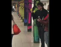 Subway musician plays guitar and sings, two guys bow their heads up and down the to beat