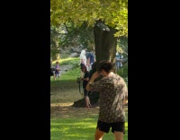 Man wearing ghillie suit filming at park