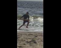 Guy throws boogie board on shore, rides on sand and gets wiped out by beach wave