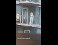 Blonde woman striped pants balcony phone tripod