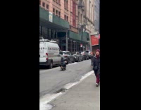 Guy rides skateboard sitting while hugging dog