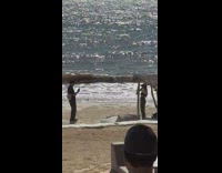 Woman in black bikini top poses while worker takes picture