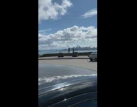 Two girls stand stone wall beach parking 