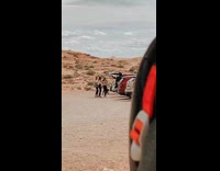 Three women back of car dance desert