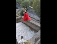 Woman in red dress ballerina pose on the balcony edge