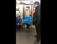 Man in blue dreidel spins around in subway train 