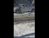 Guy trying to shovel out snow from under his truck with a broom 
