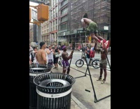 Shirtless guy spins around metal bar on sidewalk 