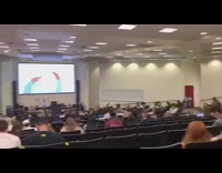 Two guys chase each other in towels in the middle of college lecture class
