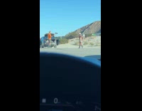 Man shirtless with black boots and cowboy hat poses near the railroad