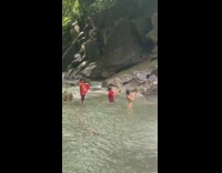 Woman in red bikini poses by the falls with three photographer