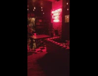 Woman poses near the neon light sign at the bar