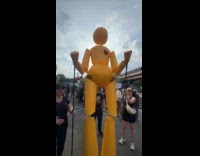 Large yellow humanoid puppets dance at park