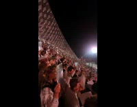 Crowd sings and holds shiny reflective paper