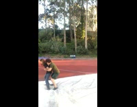 Two guys practice wrestling move on white safety pad on running track