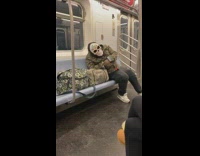 Guy in camouflage jacket and skull candy mask sleeps on subway train