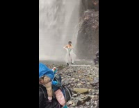 Woman hold white cloth near waterfalls rocks