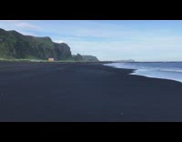 View of black sand beach grass mountains