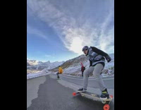 Guy rides skateboard down mountain street friend