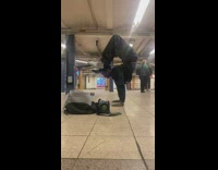 Guy in subway train station doing flexible scorpion handstand 
