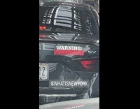 Black car has warning sticker 