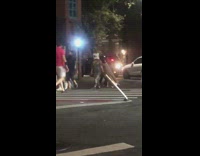 Person wearing white box over head crosses street