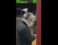Guy wearing clear bubble mask looks phone 