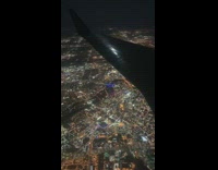 Guy looks out airplane window city lights 