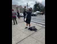 Guy photographs teddy bear wearing grey sweater