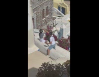 Girl hold hat pose sit ledge Santorini