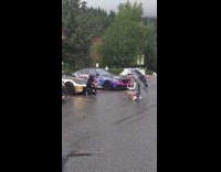 Woman with black helmet poses in front of a racecar
