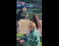 A woman selfies with two camera phone while a man films her in front