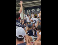 Man holds baby up at ball game people cheer