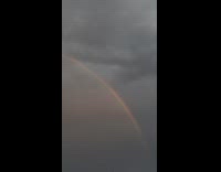 Rainbow arc on cloudy sky