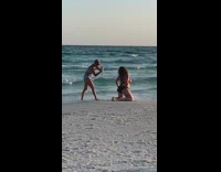 Woman black bikini kneel touch butt beach