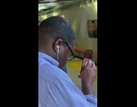 Man with glasses blue shirt watches porn closely with phone at eye level