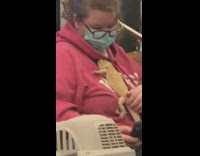 Lady riding subway has bearded dragon on chest 