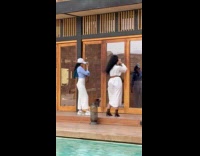 Two women poses glass door near pool