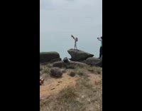 Girl lift brown dog on rock hike.