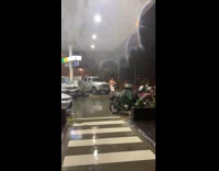 Guy standing in rain with only towel around waist at gas station