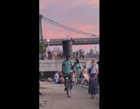 Man ride bike balance trash barrel on head shore