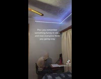 Guy white hoodie sitting at desk laughing to himself 