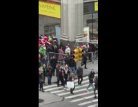 People dressed as Santas wait in line outside 