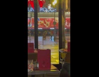 Woman poses in front of the Moulin Rouge 