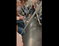 Woman holds tall wood pole on box cart on subway train