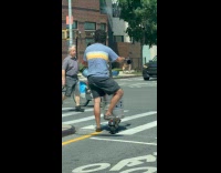 Man transporting metal barrel on electric scooter 